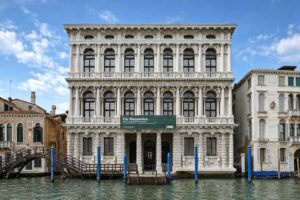 Ca' Rezzonico - Venedig - Außenansicht: Die prächtige Barockfassade des Palastes Ca' Rezzonico vom Canal Grande aus gesehen mit den typischen blauen Anlegepfählen