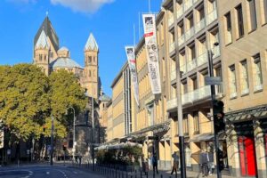 Kollwitz Museum Köln - Außenansicht: Straßenansicht am Neumarkt mit Museumsfahnen und der romanischen Kirche St. Aposteln