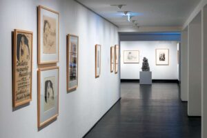 Kollwitz Museum - Köln - Ausstellung "Akte und Liebesszene": Gerahmte Zeichnungen an weißer Wand und eine Bronzeplastik auf Sockel