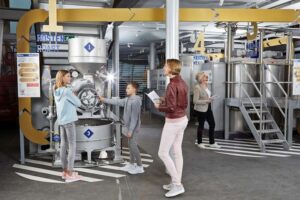 Schokoladenmuseum Köln - Gläserne Schokoladenfabrik: Besucher betrachten die Produktionsmaschinen zum Rosten und Mischen von Kakaobohnen