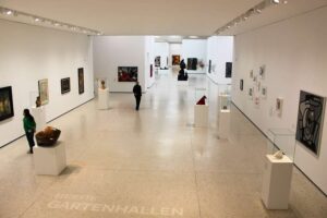 Städel Museum - Frankfurt am Main - Gartenhallen: Großer weißer Ausstellungsraum mit moderner Kunst, Skulpturen auf Sockeln und Schriftzug im Boden.